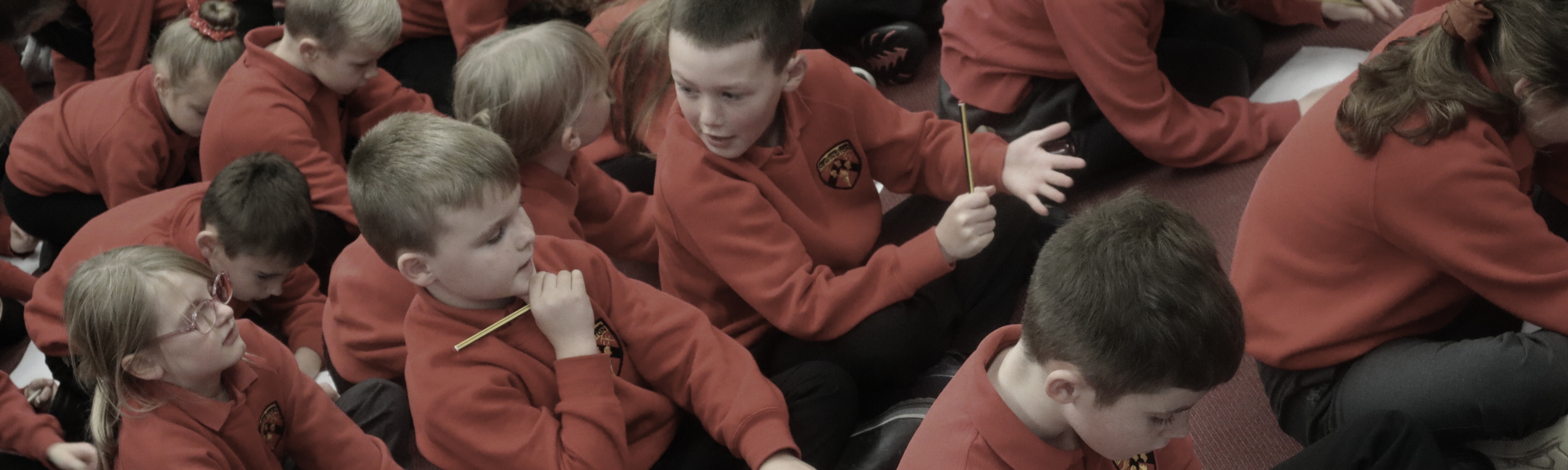 School children sitting on the floor talking and writing at a children's Book Festival event.