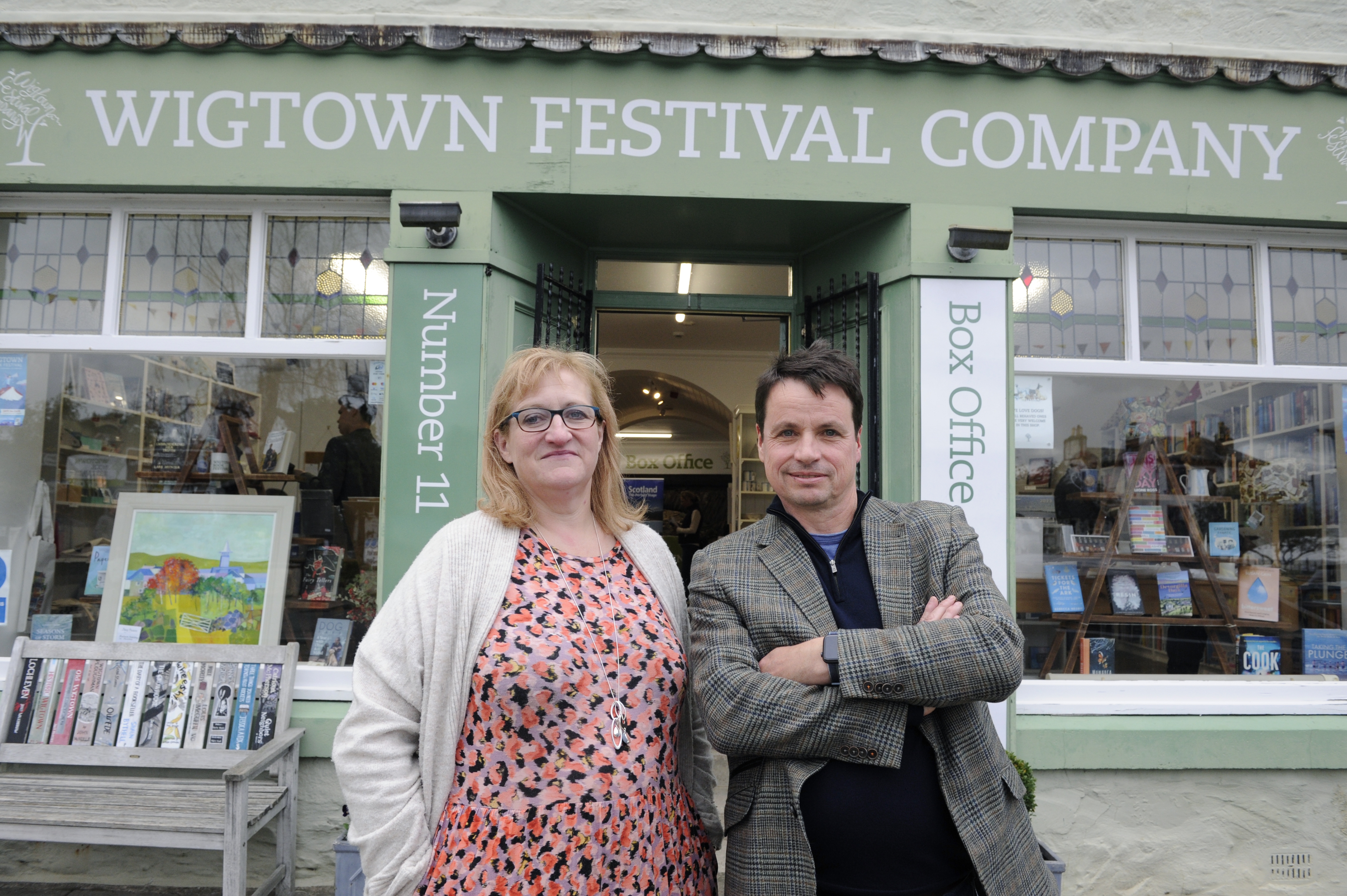 Adrian Turpin and Jo Lawrence stands in front of the Wigtown Festival Company bookshop and box office.