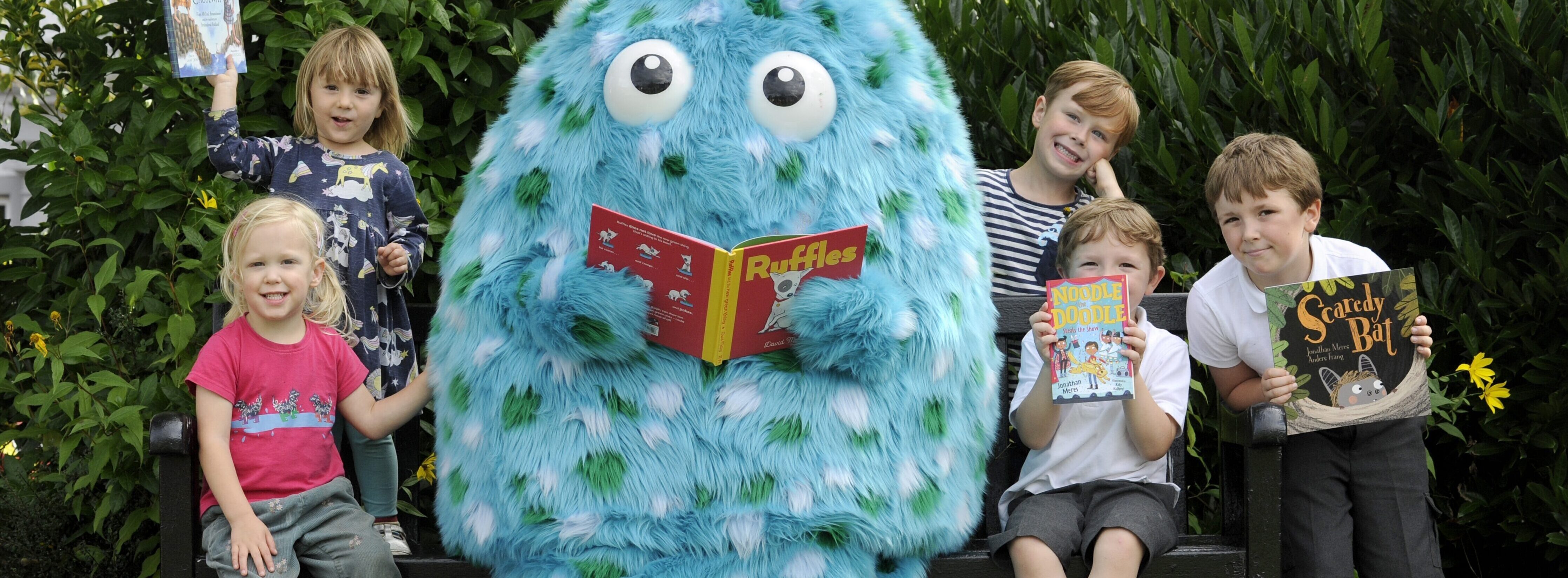 Children with books and Big Wig - the Wigtown children's book festival mascot, which is large and blue with green and white spots