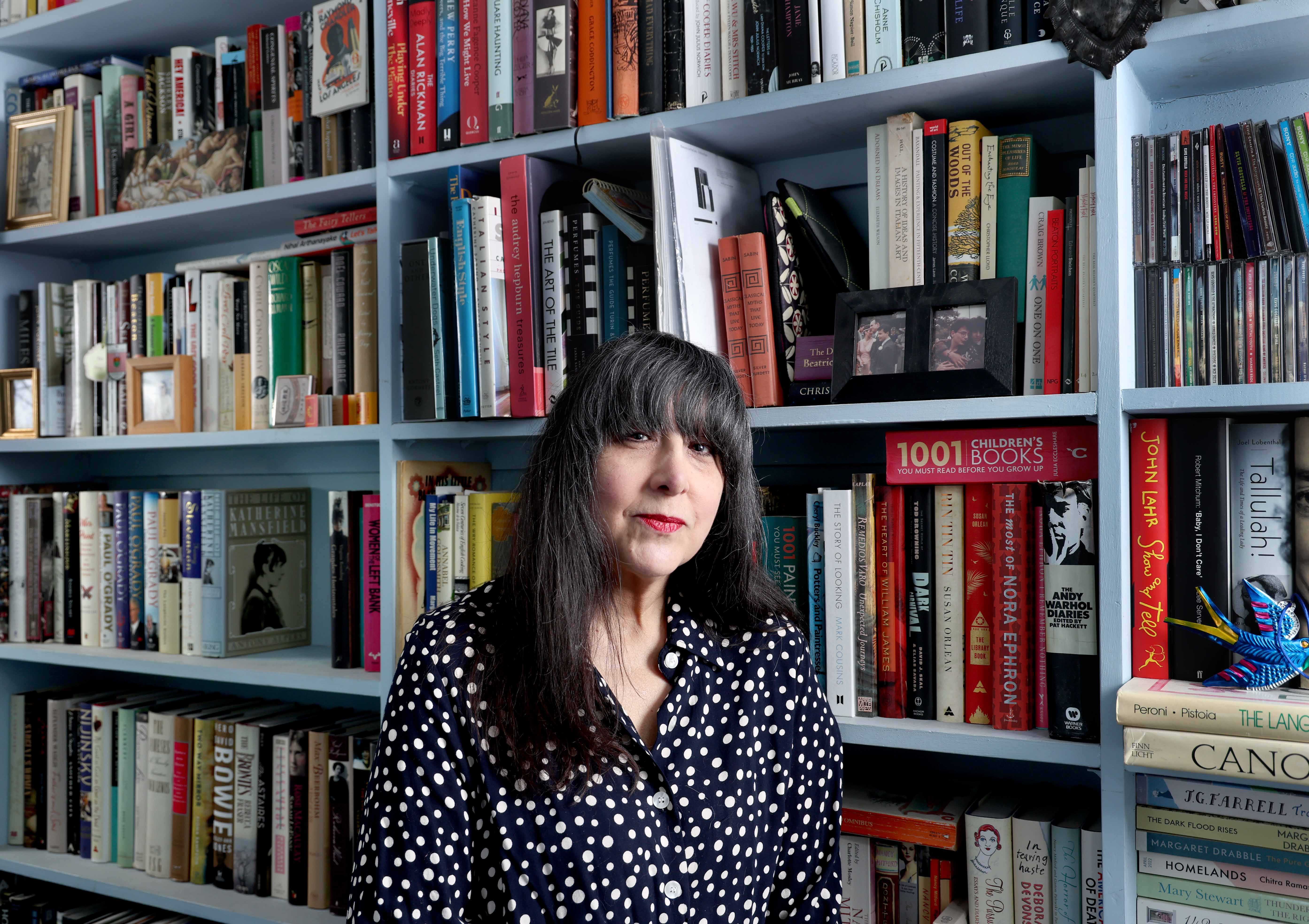 Lee Randall standing in a bookshop. The bookshelves behind her are full of books.