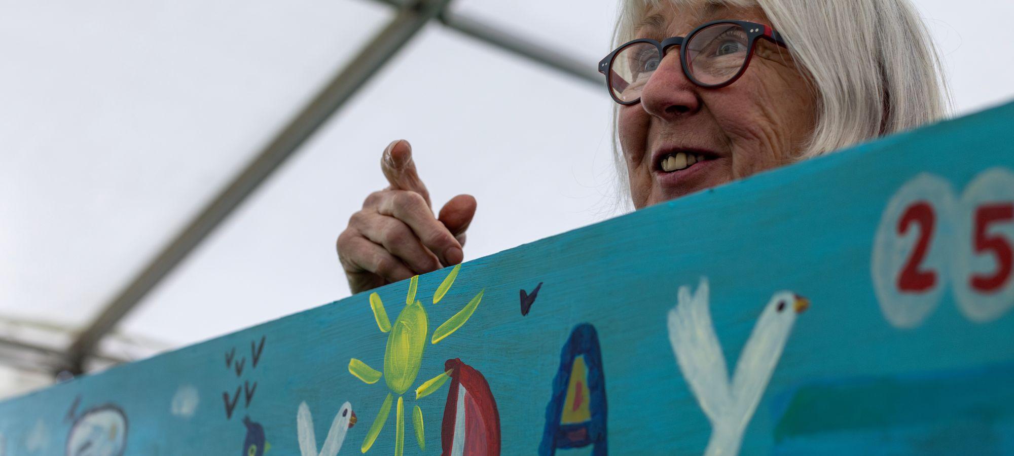 At a children's book event a volunteer holds up an illustrated banner with hand drawn lettering.