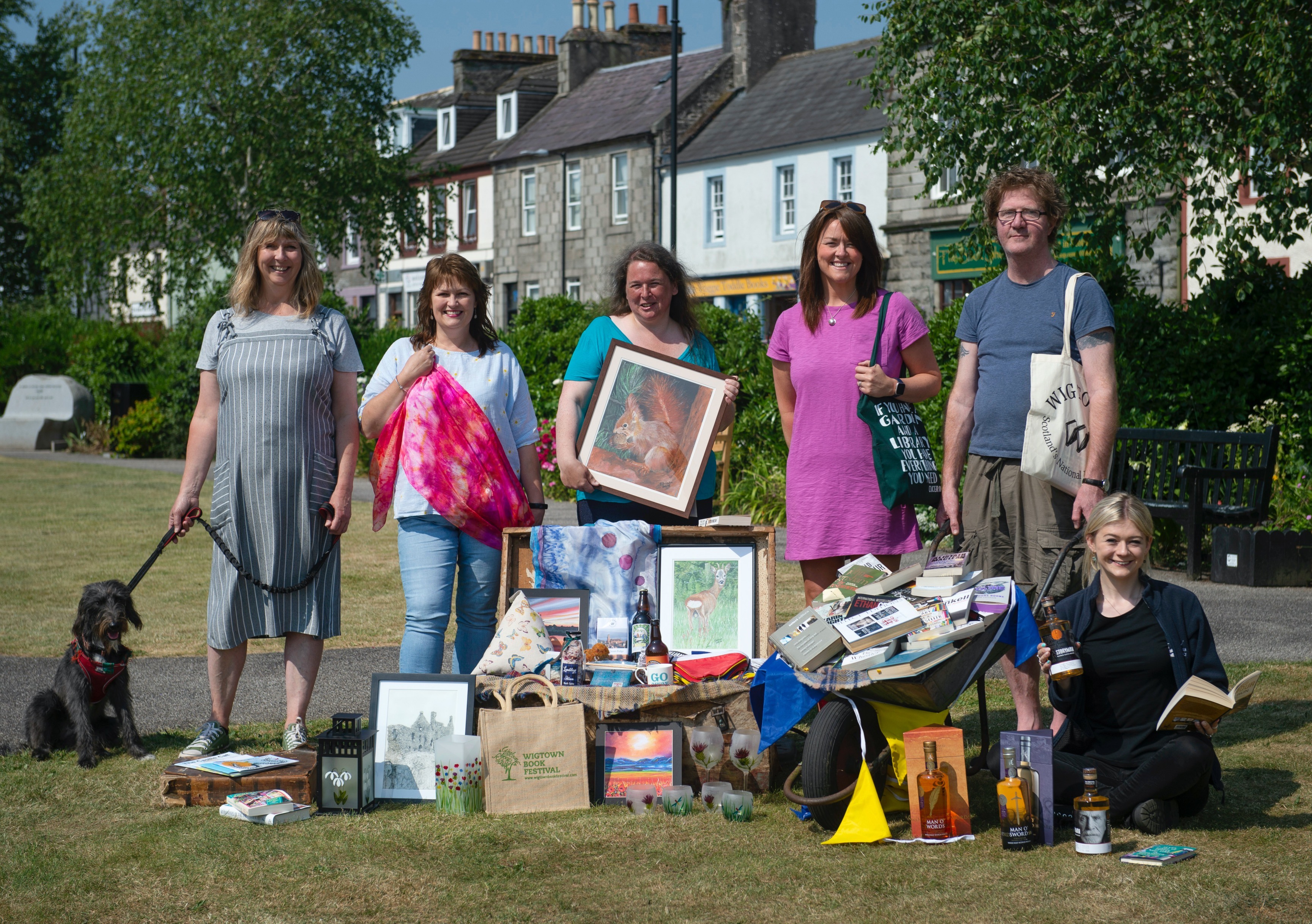 Wigtown Bookshop owners Shaun Bythell and Jane Baldwin stand in Wigtown gardens with stall holders from The Kist. They are holding various books and pictures during the Wigtown Book Festival.