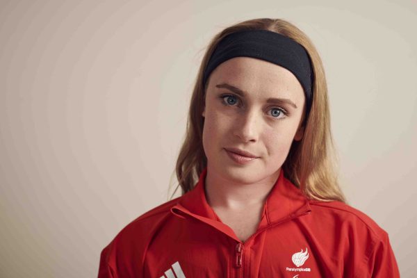 Headshot of Ellie Robinson. She is wearing a red t-shirt and a black band in her hair.