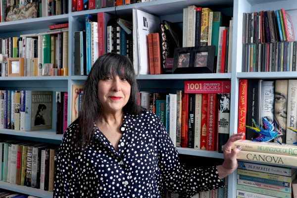 Lee Randall standing in a bookshop. The bookshelves behind her are full of books.