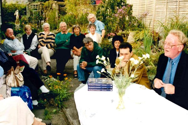 An outdoor Wigtown Book Festival event. Many people sit around in a garden listening to an author talking about his book.