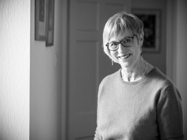 Carolyn Yates standing in front of a window, the sunlight shines onto her.